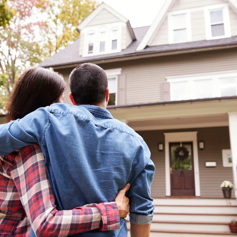 Image of a couple standing next to their house after relocating