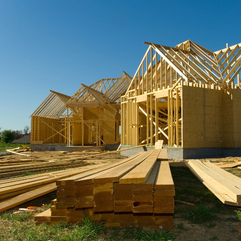 image of an under construction house with a wooden frame and wood logs lying on the floor